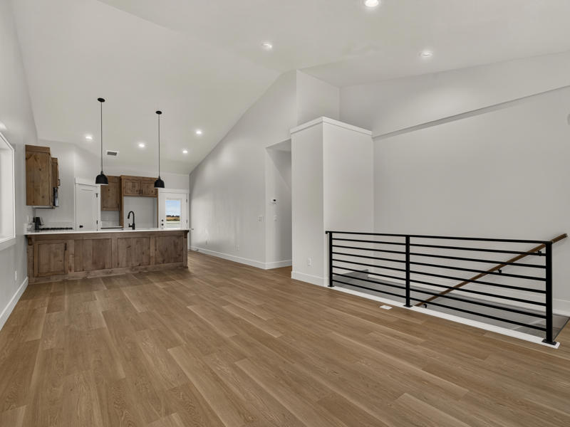 Open living area with wood floors and a black metal stair railing